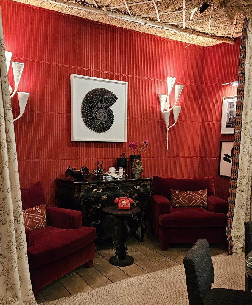 The dinning room designed by Joy Moyler has a vibrant red wall with a side room divided with drapes, perfect for an after dinner gossip