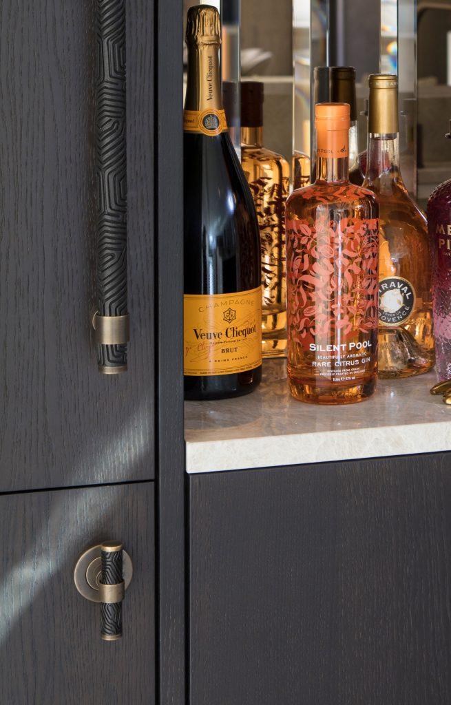A home bar cupboard unit with long intricate design pull handle for the taller door and t bar handle for under unit cupboard. The handles the Labyrinth design, a geometric, bold pattern designed around the patterns of coral.